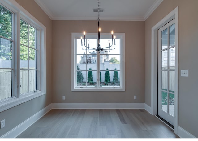 unfurnished dining area featuring light hardwood / wood-style flooring, ornamental molding, and an inviting chandelier