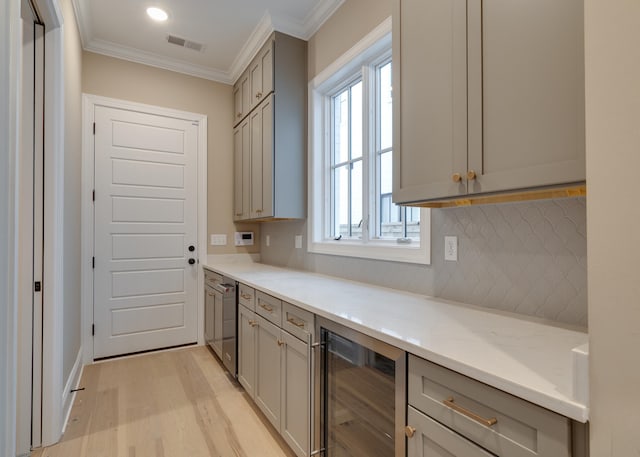 kitchen featuring gray cabinetry, light stone countertops, wine cooler, crown molding, and light hardwood / wood-style floors