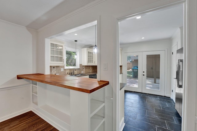 kitchen with french doors, crown molding, decorative backsplash, butcher block countertops, and decorative light fixtures