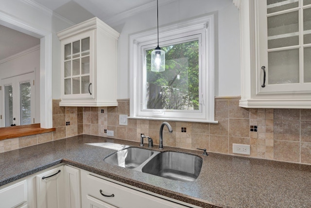 kitchen with backsplash, decorative light fixtures, white cabinetry, and sink