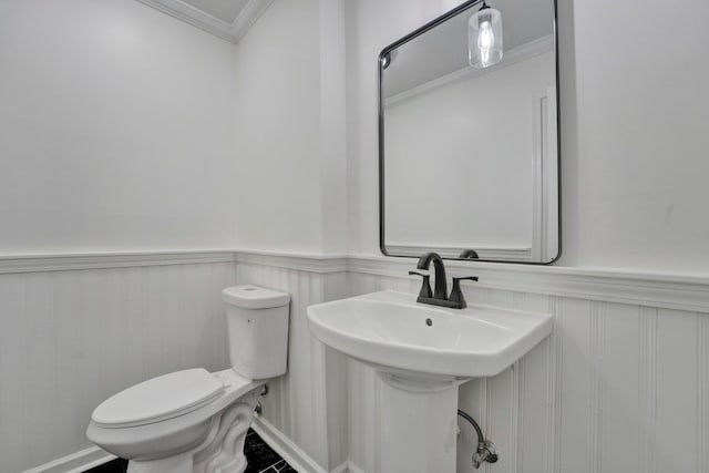 bathroom featuring toilet, crown molding, and sink