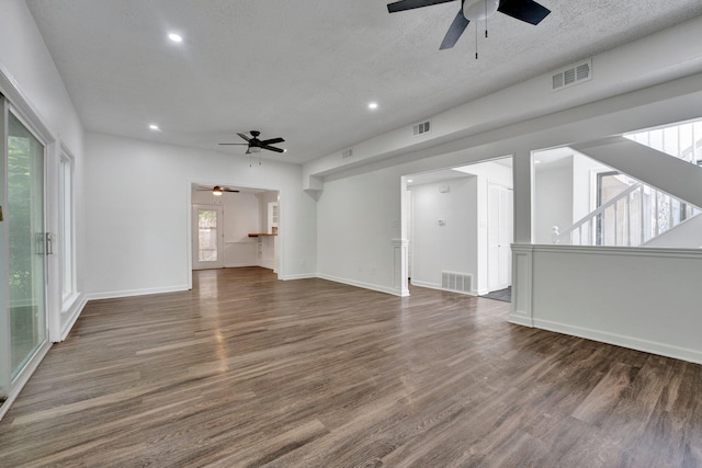 unfurnished living room with a textured ceiling, dark hardwood / wood-style floors, and a wealth of natural light