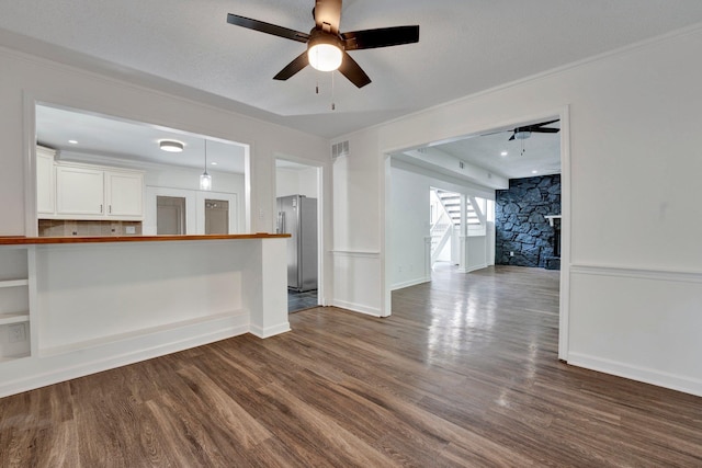 unfurnished living room featuring dark hardwood / wood-style flooring, ceiling fan, and ornamental molding