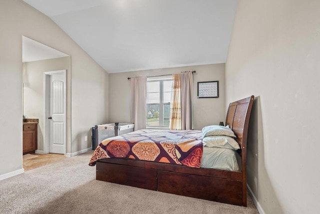 carpeted bedroom with ensuite bathroom and vaulted ceiling