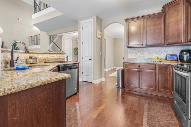 kitchen featuring light stone countertops, sink, dark wood-type flooring, stainless steel appliances, and backsplash