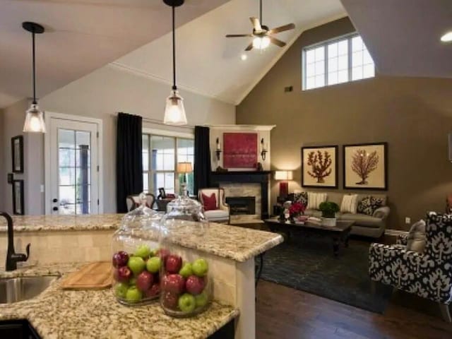 kitchen with dark hardwood / wood-style floors, light stone countertops, sink, and decorative light fixtures