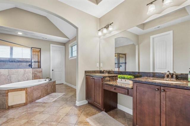 bathroom featuring tile patterned flooring, vanity, a relaxing tiled tub, and lofted ceiling