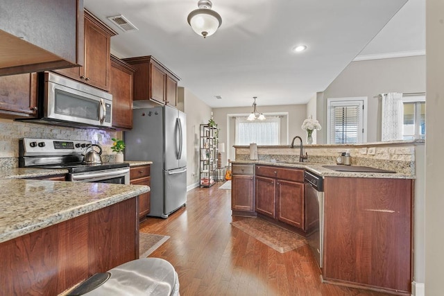 kitchen featuring sink, stainless steel appliances, light stone counters, crown molding, and light hardwood / wood-style floors