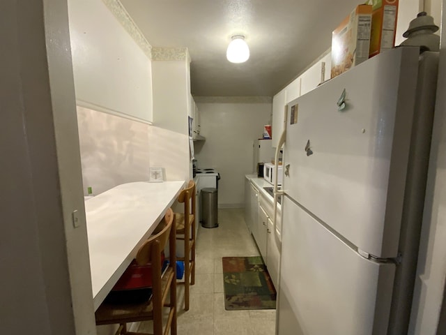 kitchen with white fridge and white cabinetry