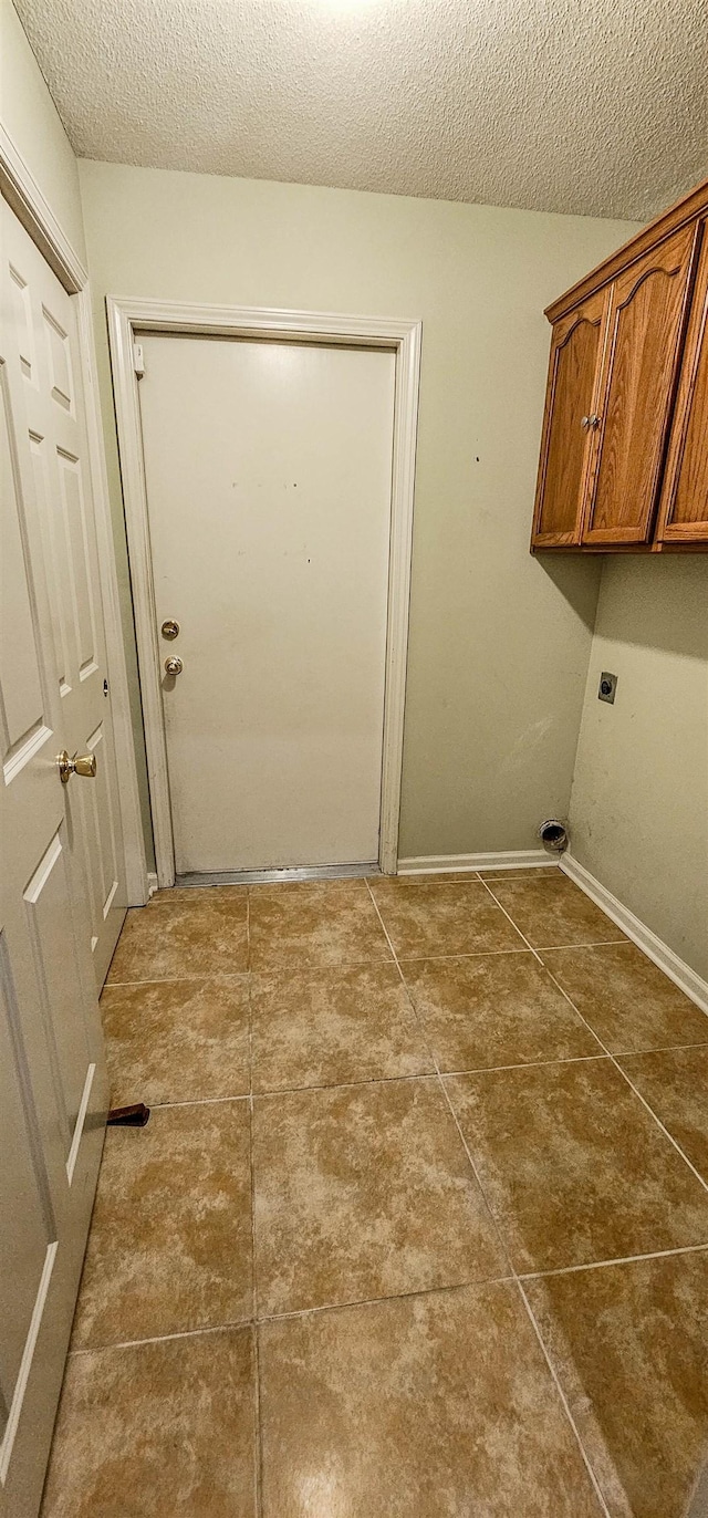 laundry area with dark tile patterned flooring, cabinets, a textured ceiling, and hookup for an electric dryer