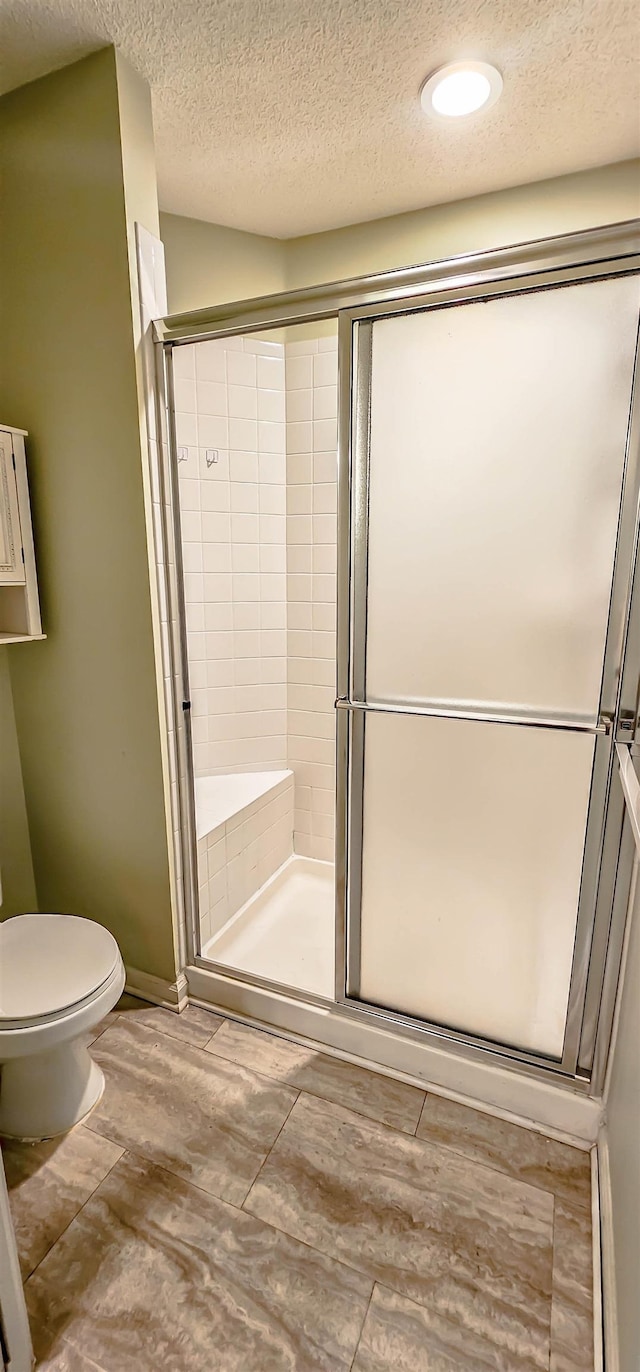 bathroom featuring hardwood / wood-style floors, a textured ceiling, toilet, and an enclosed shower