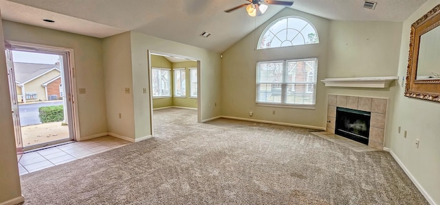 unfurnished living room featuring light carpet, high vaulted ceiling, ceiling fan, and a tiled fireplace