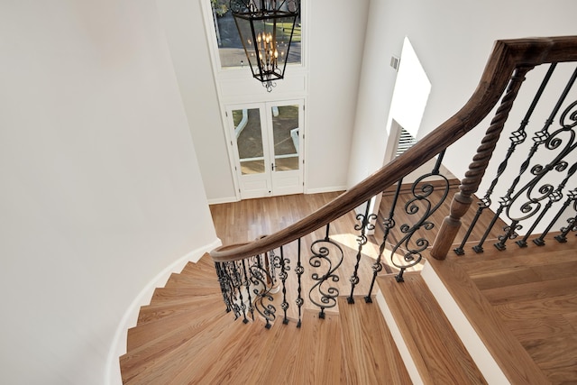 stairs featuring hardwood / wood-style floors and an inviting chandelier