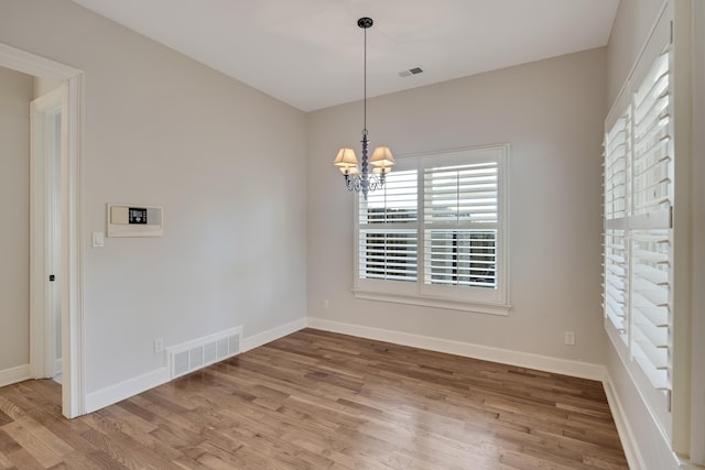 unfurnished dining area with hardwood / wood-style flooring and a notable chandelier