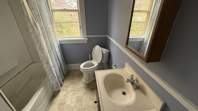 full bathroom featuring shower / bath combination with curtain, a healthy amount of sunlight, toilet, and sink