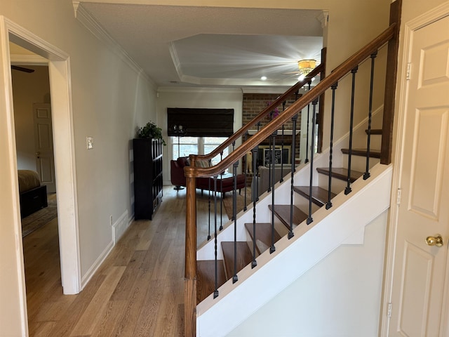 stairs with ornamental molding and hardwood / wood-style flooring