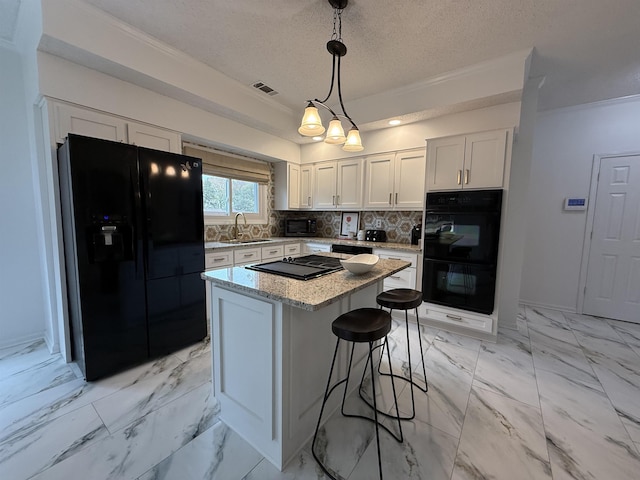 kitchen featuring white cabinetry, hanging light fixtures, tasteful backsplash, a kitchen island, and black appliances