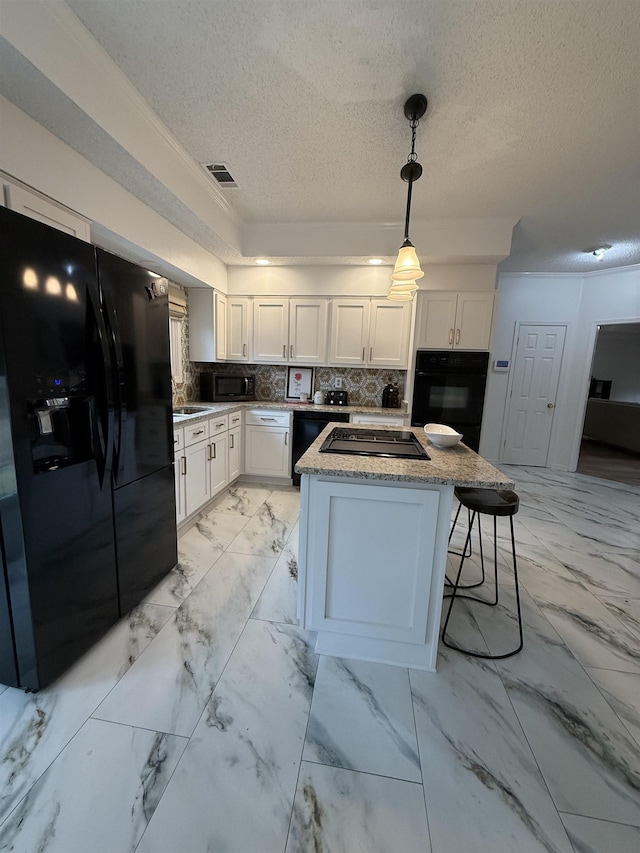 kitchen featuring white cabinetry, tasteful backsplash, a textured ceiling, a kitchen island, and black appliances