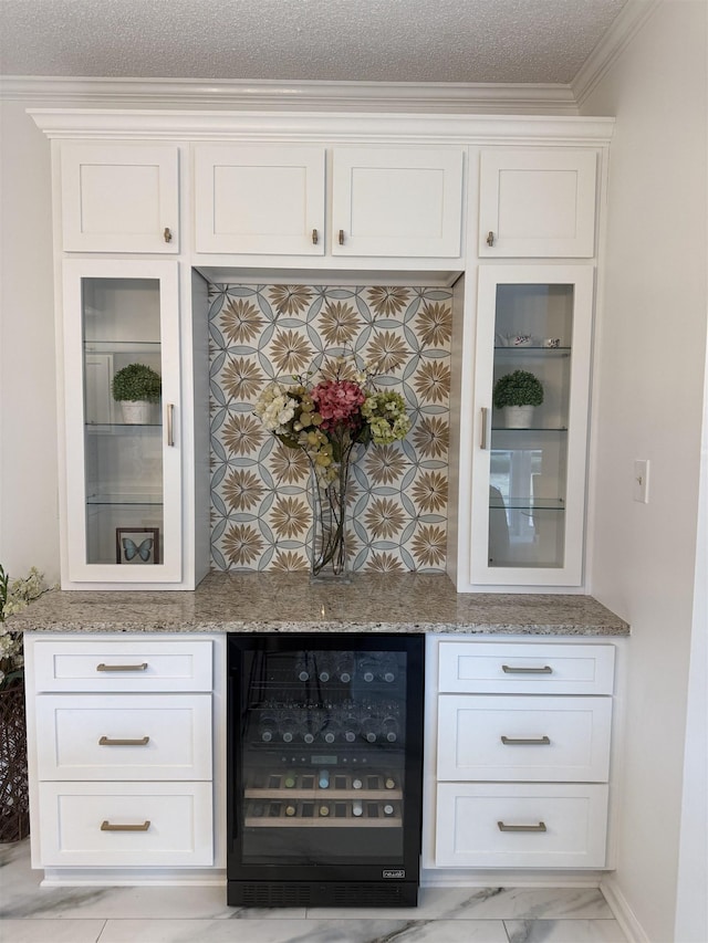 bar with light stone countertops, wine cooler, crown molding, a textured ceiling, and white cabinets