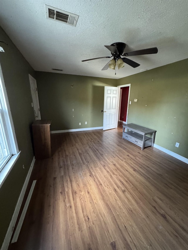 interior space with ceiling fan, wood-type flooring, and a textured ceiling