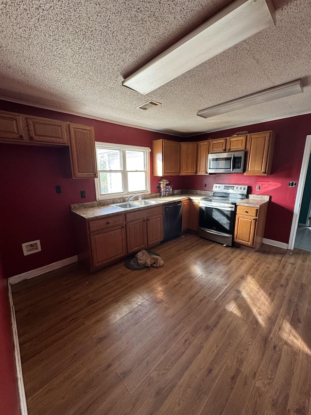 kitchen with sink, a textured ceiling, dark hardwood / wood-style floors, and stainless steel appliances