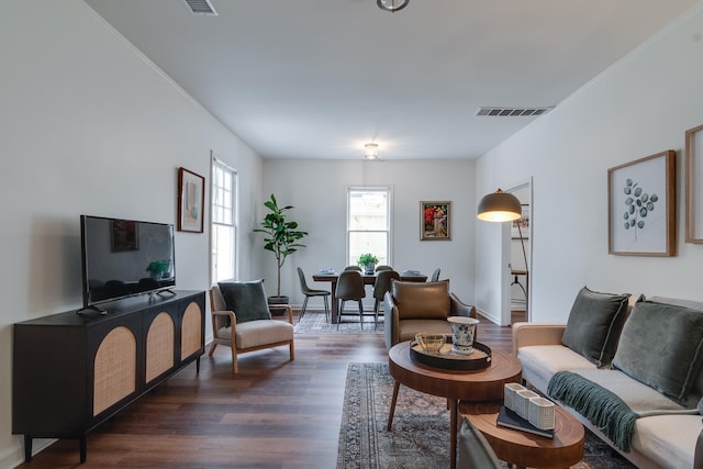 living room with dark wood-type flooring and ornamental molding