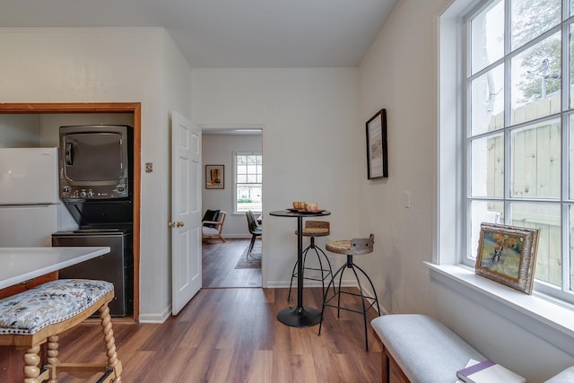 hall featuring stacked washer / dryer, a healthy amount of sunlight, and dark hardwood / wood-style floors