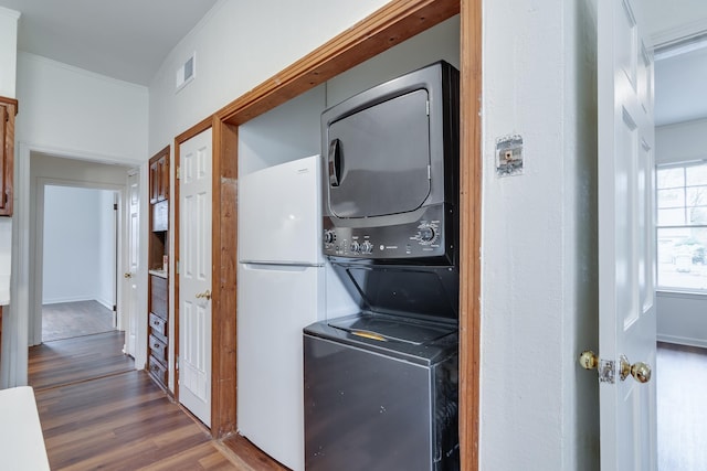 laundry room with dark hardwood / wood-style floors and stacked washer and clothes dryer