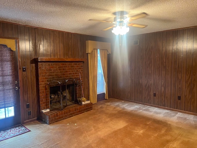 unfurnished living room featuring a fireplace, carpet floors, ceiling fan, and wooden walls