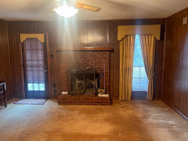 unfurnished living room with wood walls, a fireplace, carpet floors, and a textured ceiling