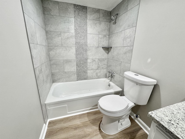 full bathroom with hardwood / wood-style floors, tiled shower / bath combo, toilet, and vanity