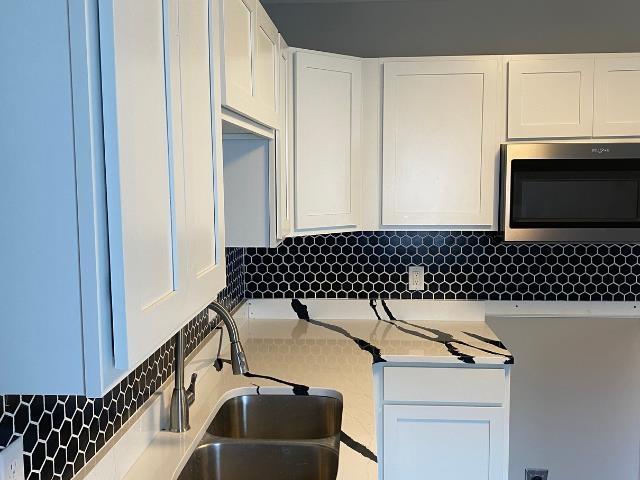 kitchen featuring tasteful backsplash, white cabinetry, and sink