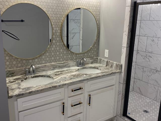 bathroom featuring vanity, a shower with door, and tasteful backsplash