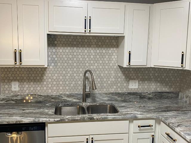 kitchen featuring stainless steel dishwasher, white cabinetry, and sink