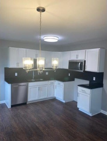 kitchen with backsplash, sink, dark hardwood / wood-style floors, appliances with stainless steel finishes, and white cabinetry