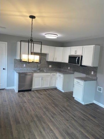 kitchen featuring stainless steel appliances, white cabinetry, dark hardwood / wood-style floors, and sink