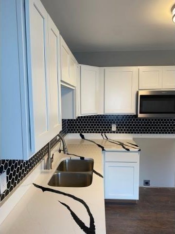 kitchen with white cabinetry, decorative backsplash, sink, and dark wood-type flooring