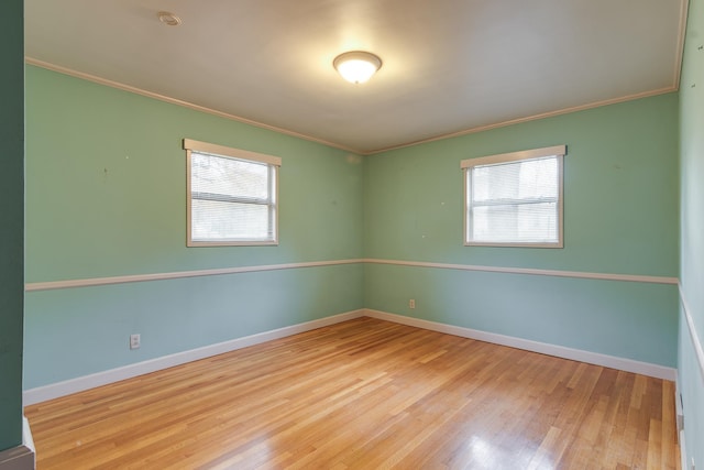 empty room featuring light wood-type flooring, crown molding, and a healthy amount of sunlight