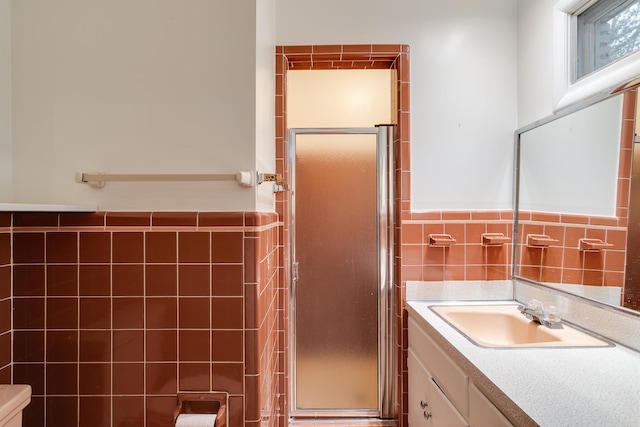 bathroom featuring vanity, a shower with shower door, and tile walls