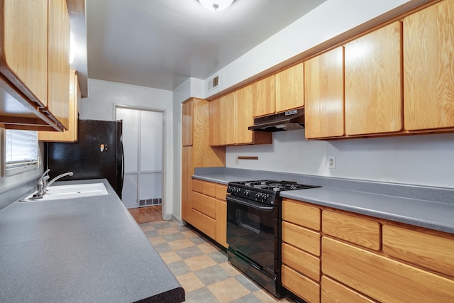 kitchen featuring light brown cabinetry, sink, and black appliances