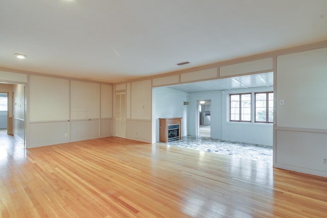 unfurnished living room featuring light hardwood / wood-style flooring and ornamental molding