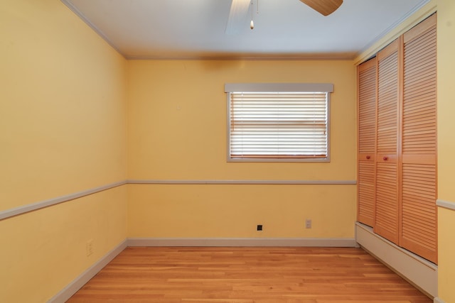 unfurnished bedroom featuring ceiling fan, light hardwood / wood-style floors, crown molding, and a closet