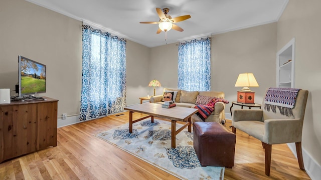 living room with hardwood / wood-style flooring, ceiling fan, and ornamental molding