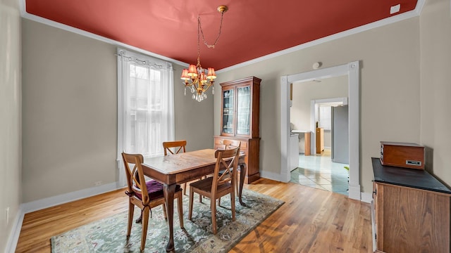 dining space with crown molding, light hardwood / wood-style flooring, and a notable chandelier