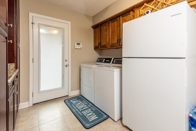 washroom featuring washing machine and dryer, light tile patterned floors, cabinets, and a textured ceiling