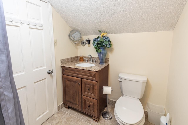 bathroom featuring toilet, vanity, a textured ceiling, and tile patterned floors