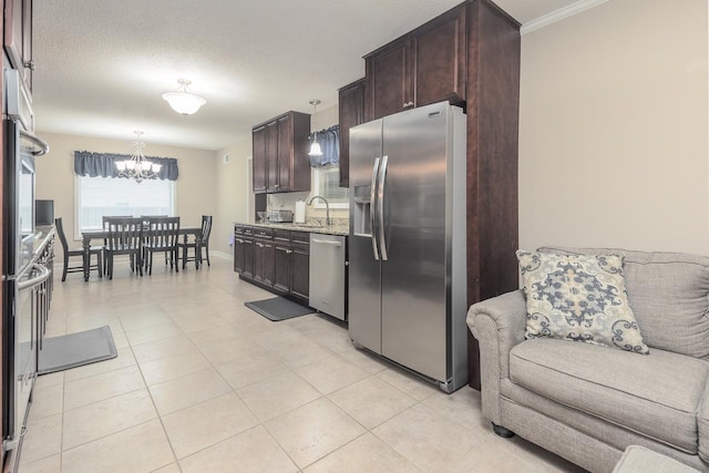 kitchen with pendant lighting, light stone countertops, appliances with stainless steel finishes, a notable chandelier, and dark brown cabinetry