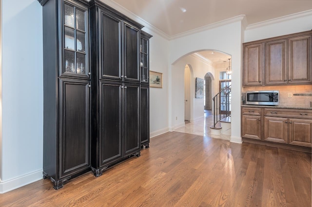 kitchen featuring stone counters, hardwood / wood-style flooring, tasteful backsplash, and crown molding