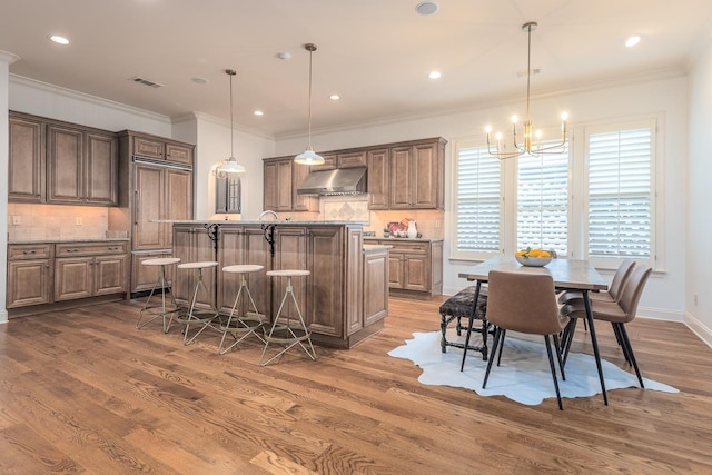 9207 Liggon Green Ln, Germantown, TN 38139 - kitchen featuring exhaust hood, dark wood-type flooring, a chandelier, a center island with sink, and backsplash