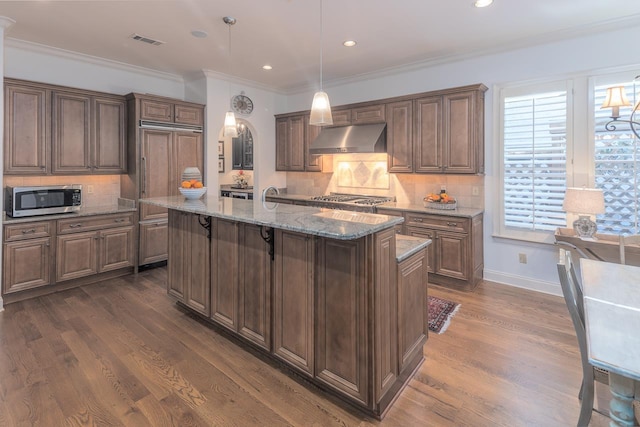 kitchen with a center island with sink, decorative backsplash, dark wood-type flooring, and appliances with stainless steel finishes